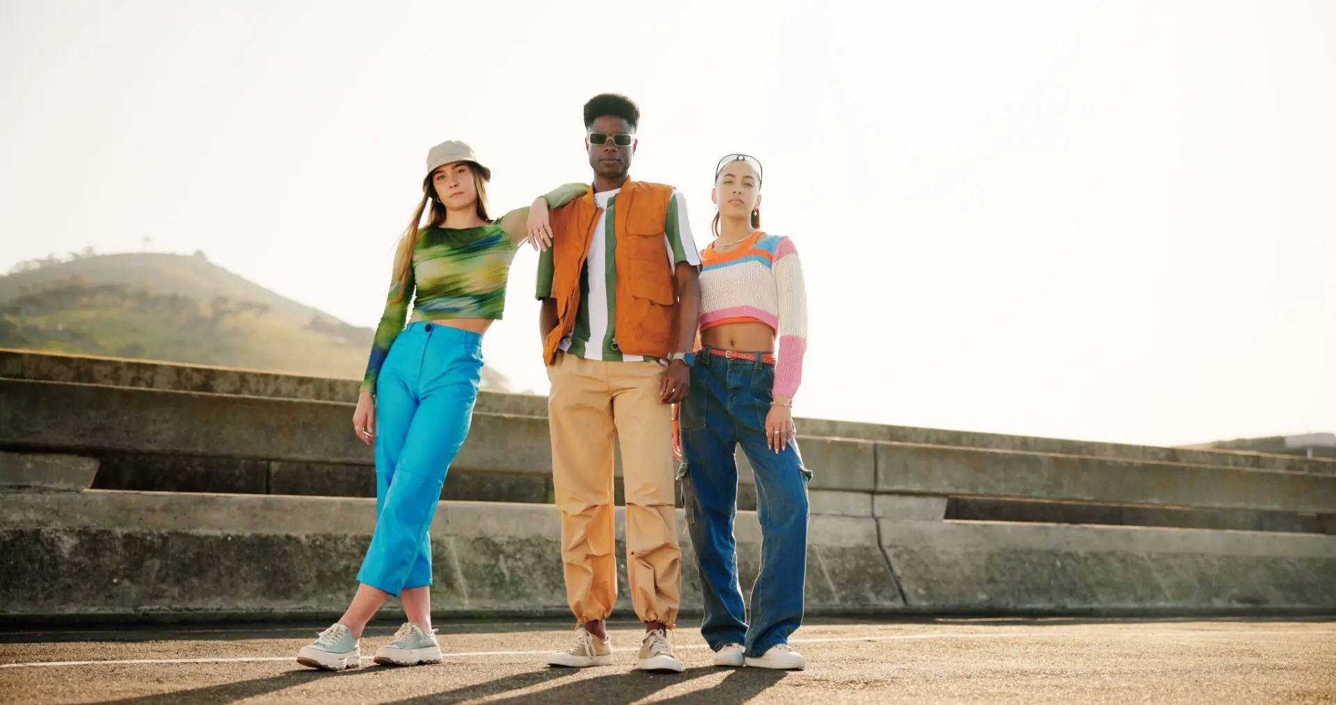 Three people posing in stylish outfits outdoors.