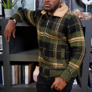 Man in a cozy plaid sweater with a shearling collar leaning on a chair.