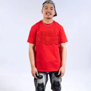 Young man in a red graphic t-shirt and black patterned pants.