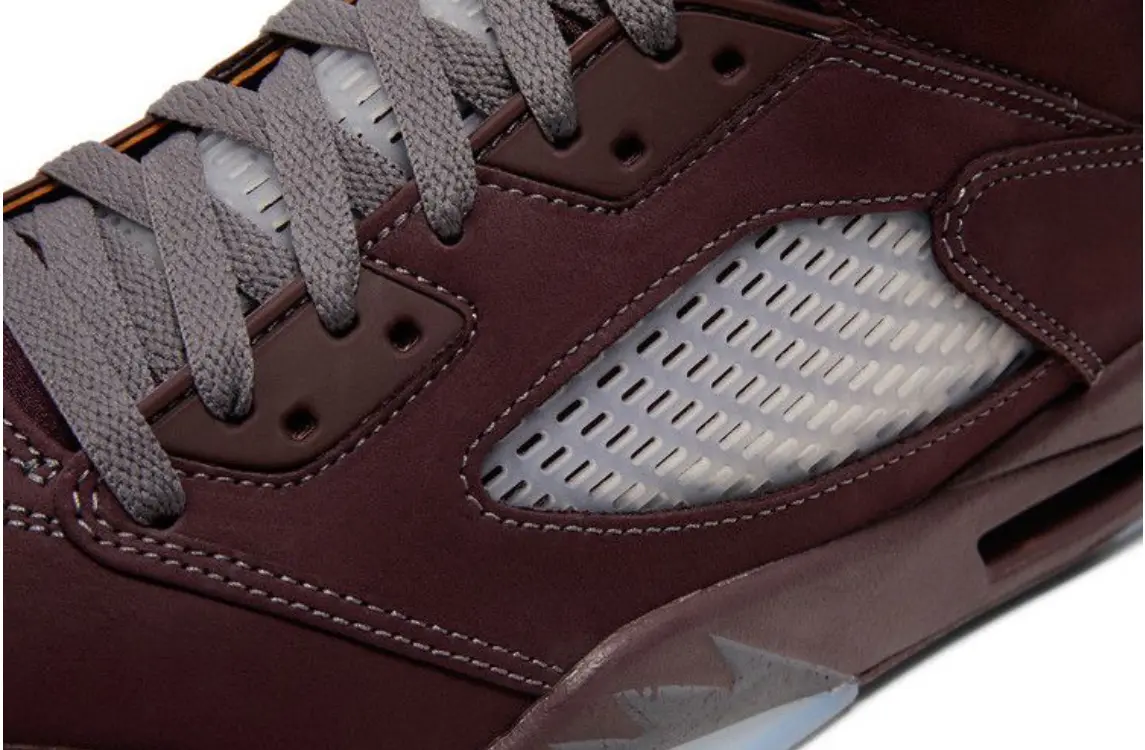 Close-up of a maroon sneaker with grey laces and mesh detailing.