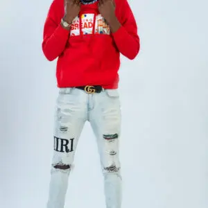 Person in a red hoodie and ripped jeans posing.