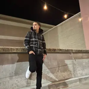Person in a checkered jacket standing on a concrete ledge at night.