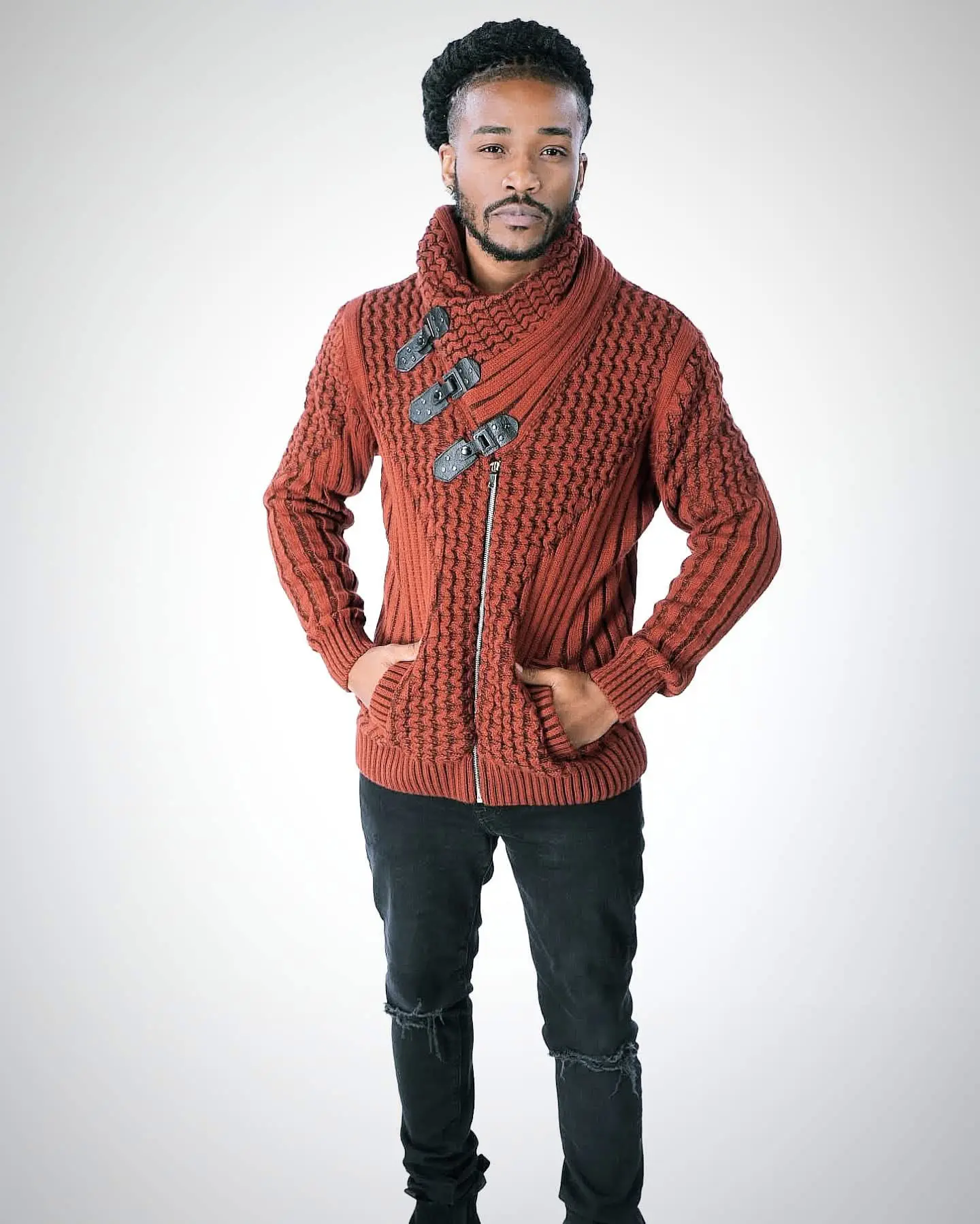 Man wearing a brown knitted cardigan with pockets and black pants.