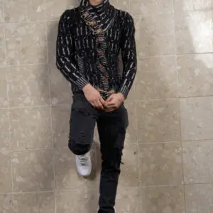 Person wearing a black patterned top and black pants with white shoes.