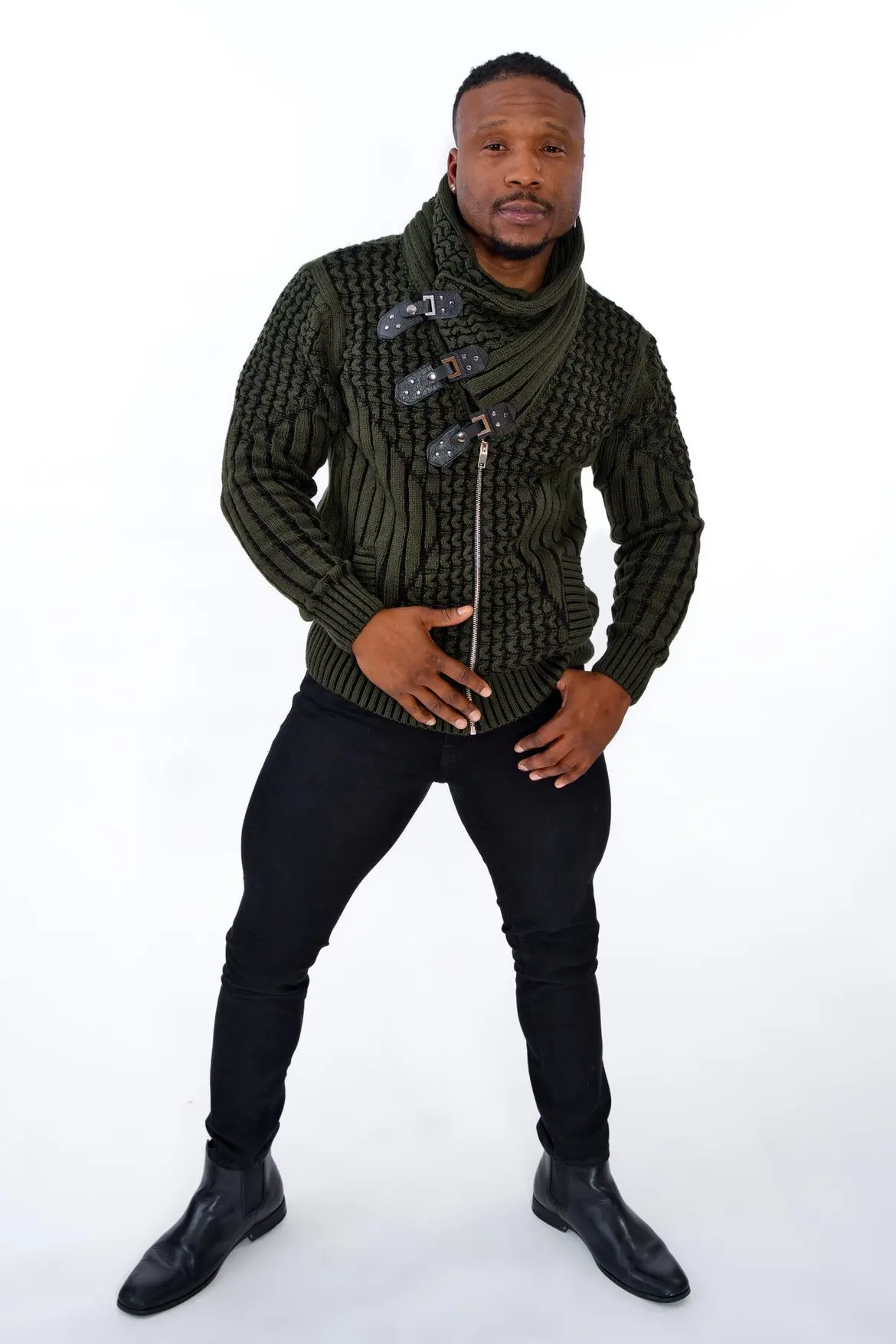 Man posing in a black patterned jacket and black pants against white background.