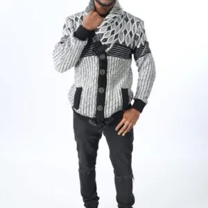 Man in a patterned sweater and black pants posing against a white background.