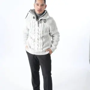Man wearing a white cable-knit sweater and black pants.