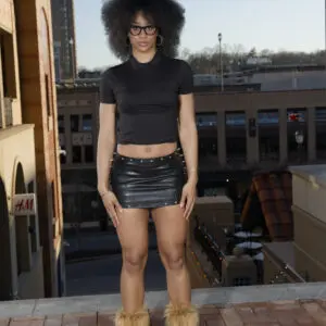 Person in black crop top and shorts standing on a rooftop at sunset.
