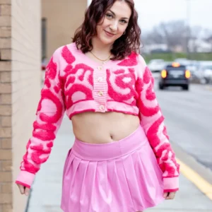 Young woman in a vibrant pink outfit posing outdoors.